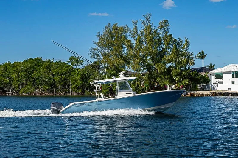 Livy Rose Yacht Photos Pics 2021 Cobia 320 Center Console boat cruising on a sunny day near lush greenery.