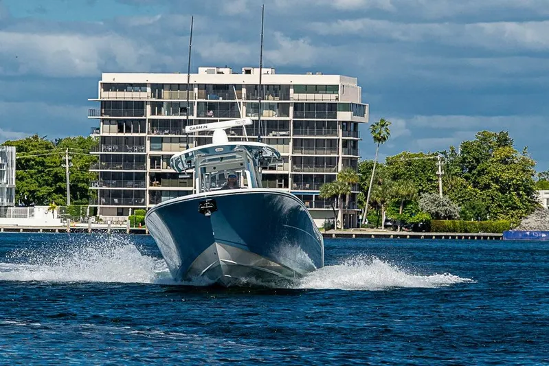 Livy Rose Yacht Photos Pics 2021 Cobia 320 Center Console boat cruising on water near modern buildings.