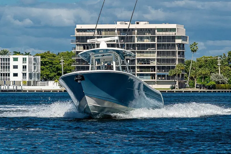 Livy Rose Yacht Photos Pics 2021 Cobia 320 Center Console boat cruising on water near modern buildings.