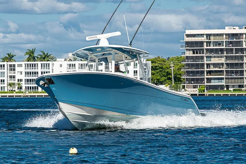 Livy Rose Yacht Photos Pics 2021 Cobia 320 Center Console boat cruising on water near waterfront buildings.