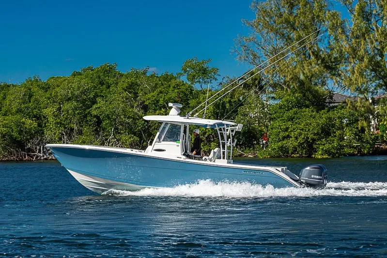Livy Rose Yacht Photos Pics 2021 Cobia 320 Center Console boat cruising on a sunny day near lush greenery.