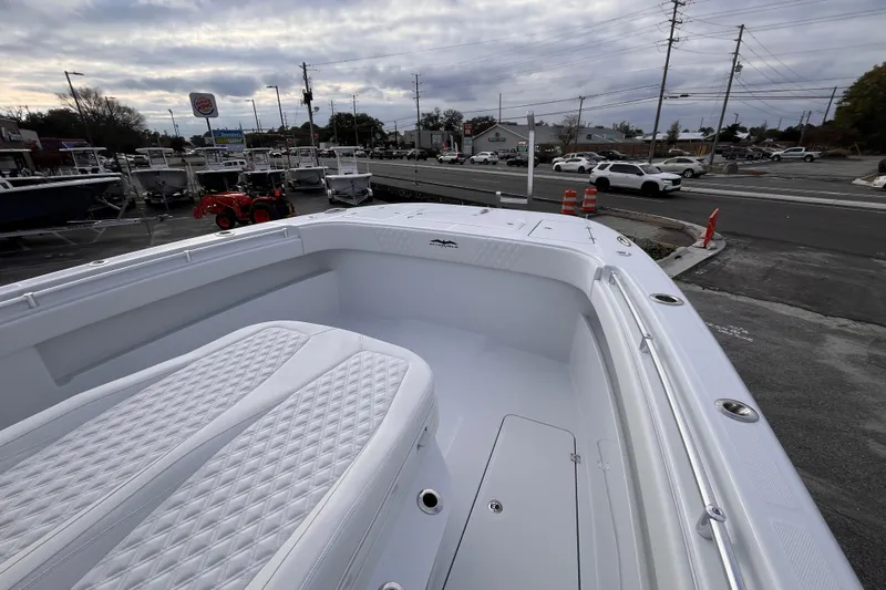  Yacht Photos Pics 2026 Invincible 33 Catamaran with white seating, parked near a dealership and road.