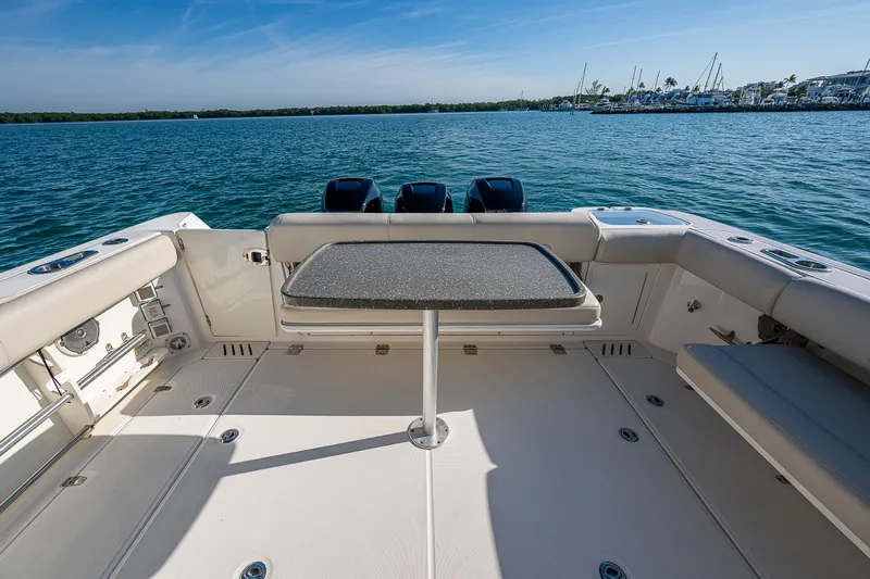  Yacht Photos Pics 2017 Boston Whaler 345 Conquest boat deck with table, overlooking serene water and marina.