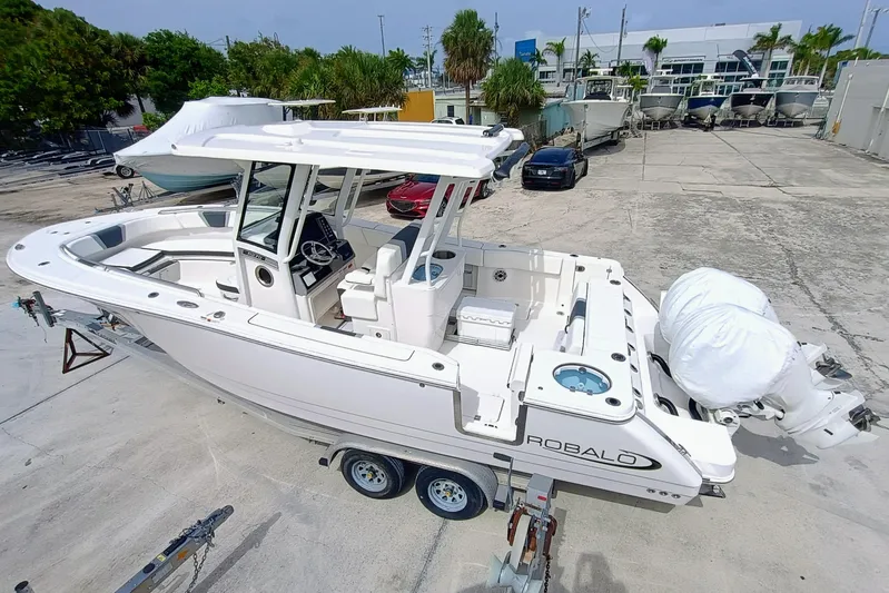 270-152 Yacht Photos Pics 2025 Robalo R270 Center Console boat on trailer, parked in a marina.