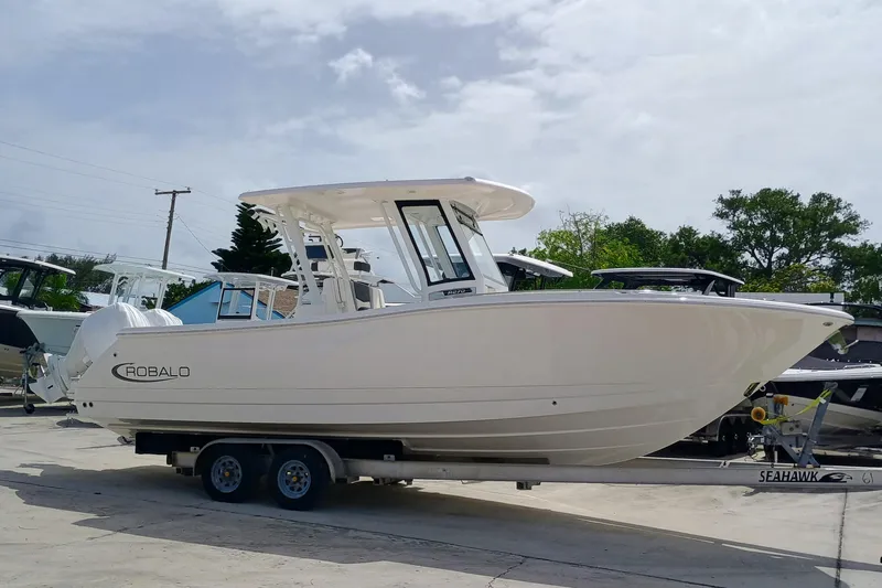 270-152 Yacht Photos Pics 2025 Robalo R270 Center Console boat on trailer, parked outdoors.