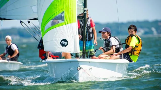 Sailors navigating an RS Quest 2025 boat on a sunny day.