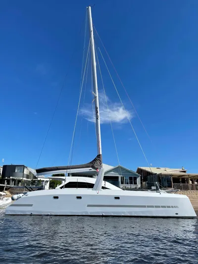  Yacht Photos Pics 2024 Schionning Arrow 1280 S catamaran docked by waterfront homes.