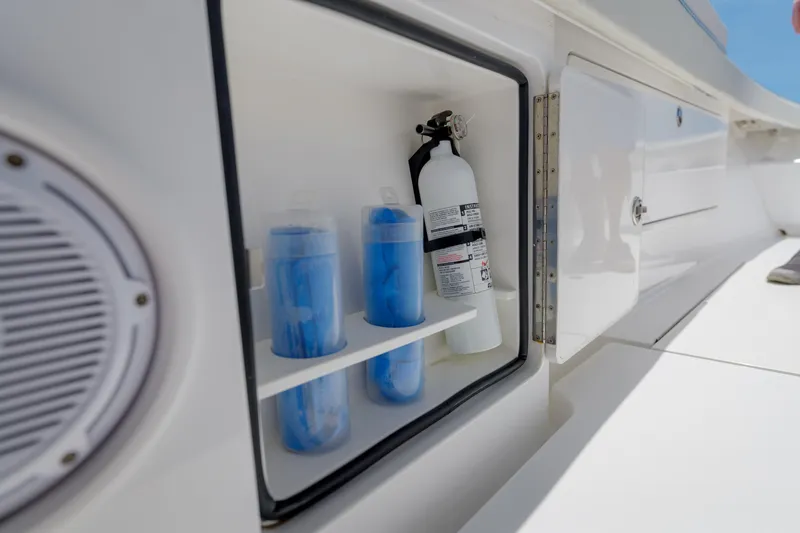 Patriot Yacht Photos Pics Open storage compartment on 2022 Valhalla Boatworks V41, featuring fire extinguisher and blue containers.