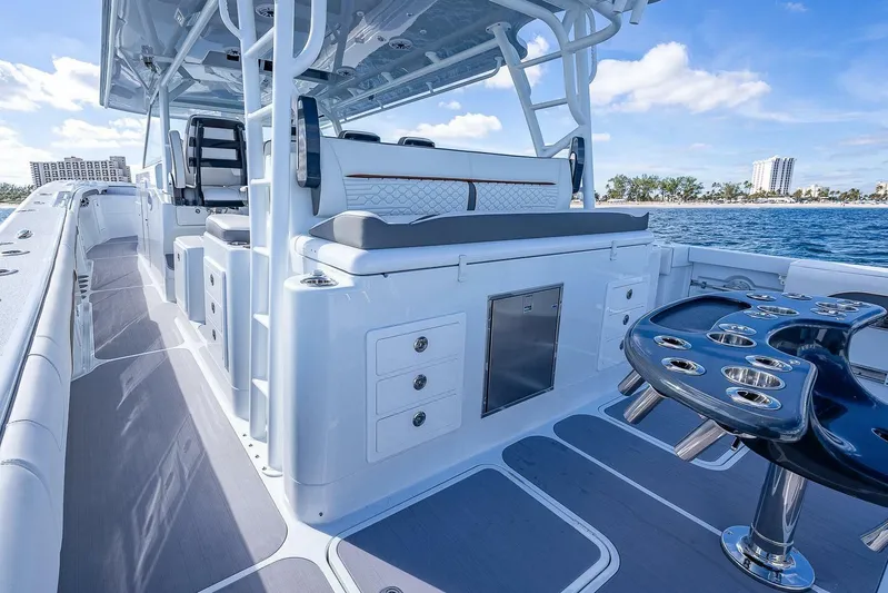  Yacht Photos Pics 2024 Yellowfin 54 Offshore boat interior with seating and rod holders, cruising on blue ocean.