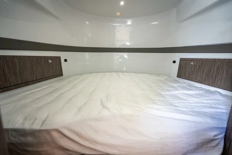  Yacht Photos Pics 2024 Yellowfin 54 Offshore cabin interior with a spacious bed and wooden storage cabinets.