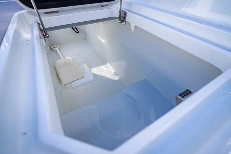  Yacht Photos Pics 2024 Yellowfin 54 Offshore storage compartment with white interior and shovel.