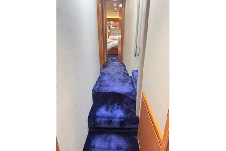  Yacht Photos Pics Luxurious blue-carpeted hallway inside a 2014 Azimut 70 yacht, leading to a bedroom.