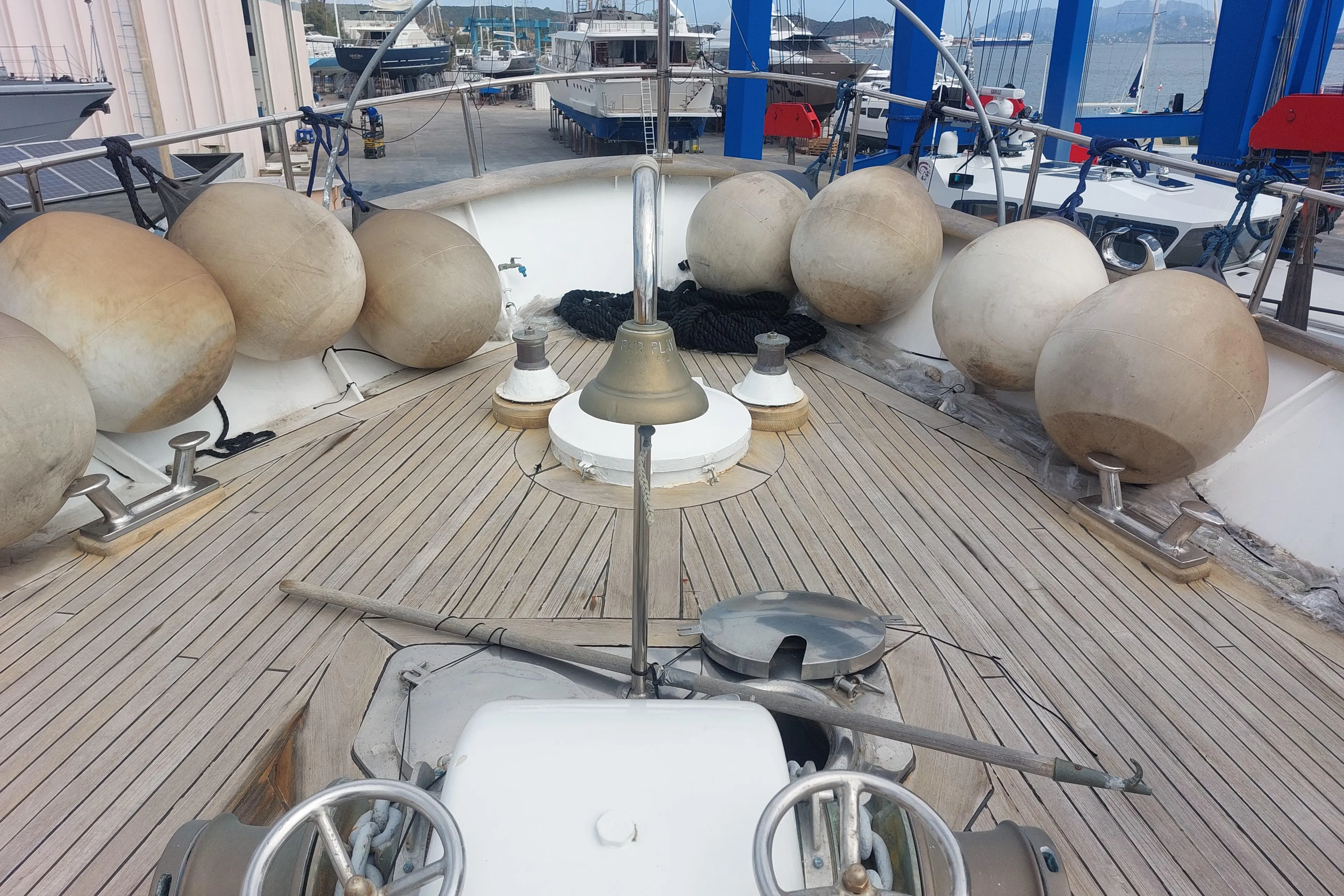 Deck of 1977 Codecasa 27m yacht with fenders and bell in a marina.