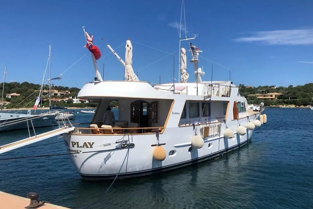 Vintage 1977 Codecasa 27m yacht docked in a scenic marina.