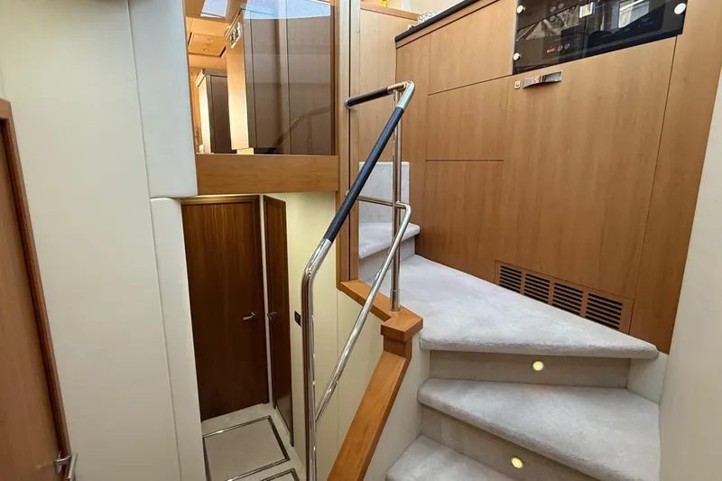 Thomas Yacht Photos Pics Interior staircase of 2012 Sunseeker Manhattan 63 yacht, featuring wood paneling and carpeted steps.