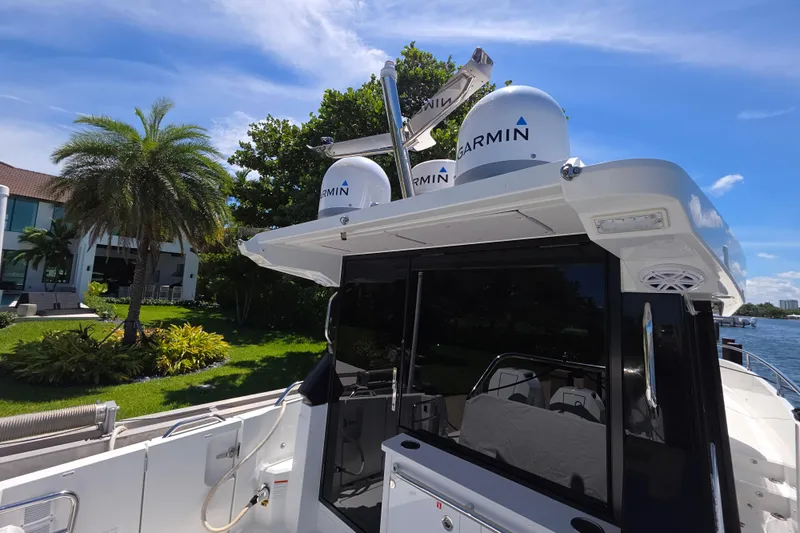  Yacht Photos Pics 2024 Wellcraft 355 Commuter boat with Garmin equipment, docked near lush greenery.