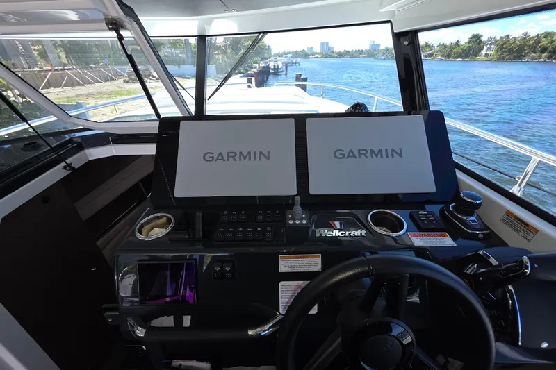  Yacht Photos Pics 2024 Wellcraft 355 Commuter helm with dual Garmin displays, steering wheel, and waterway view.