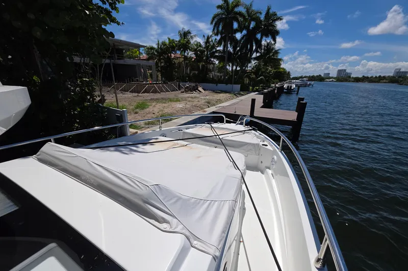  Yacht Photos Pics 2024 Wellcraft 355 Commuter boat docked by a scenic waterfront with palm trees.