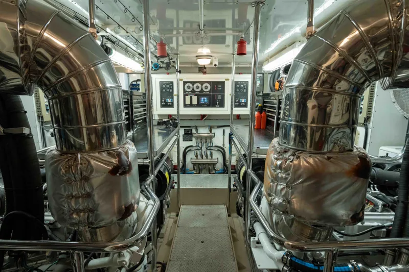 Aleniel Yacht Photos Pics Engine room of a 2005 Johnson 87' Motor Yacht with polished metal pipes and control panels.