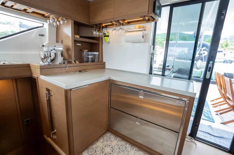  Yacht Photos Pics Modern kitchen interior on 2020 Lagoon 50 yacht, featuring wood cabinetry and stainless steel appliances.