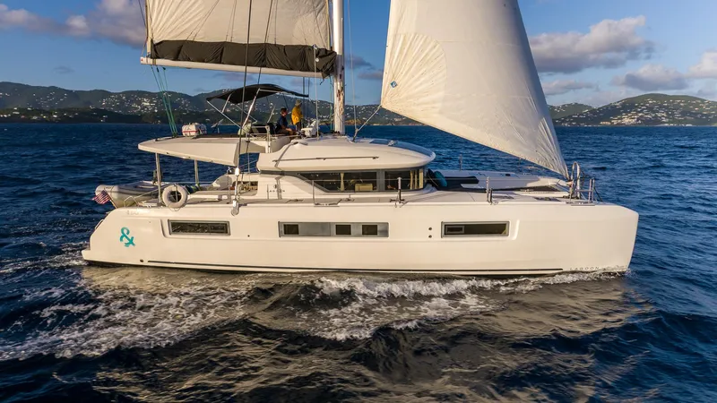  Yacht Photos Pics 2020 Lagoon 50 sailing catamaran cruising on open sea with scenic mountain backdrop.