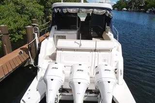  Yacht Photos Pics 2021 Regal 38 XO boat with triple outboard engines docked by a scenic waterway.