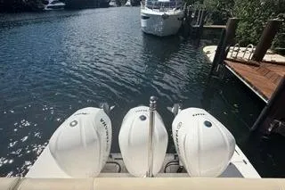  Yacht Photos Pics 2021 Regal 38 XO boat with triple outboard engines docked by a serene waterway.