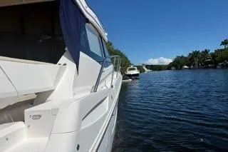  Yacht Photos Pics 2021 Regal 38 XO yacht cruising on a serene river under a clear blue sky.