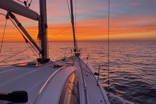 Pura Vida Yacht Photos Pics Jeanneau Sun Odyssey 42 DS sailing at sunset, 2007 model, on calm ocean waters.