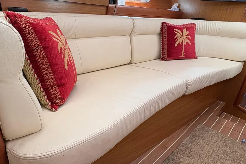 Pura Vida Yacht Photos Pics Luxurious interior of 2007 Jeanneau Sun Odyssey 42 DS with cream sofa and red palm pillows.