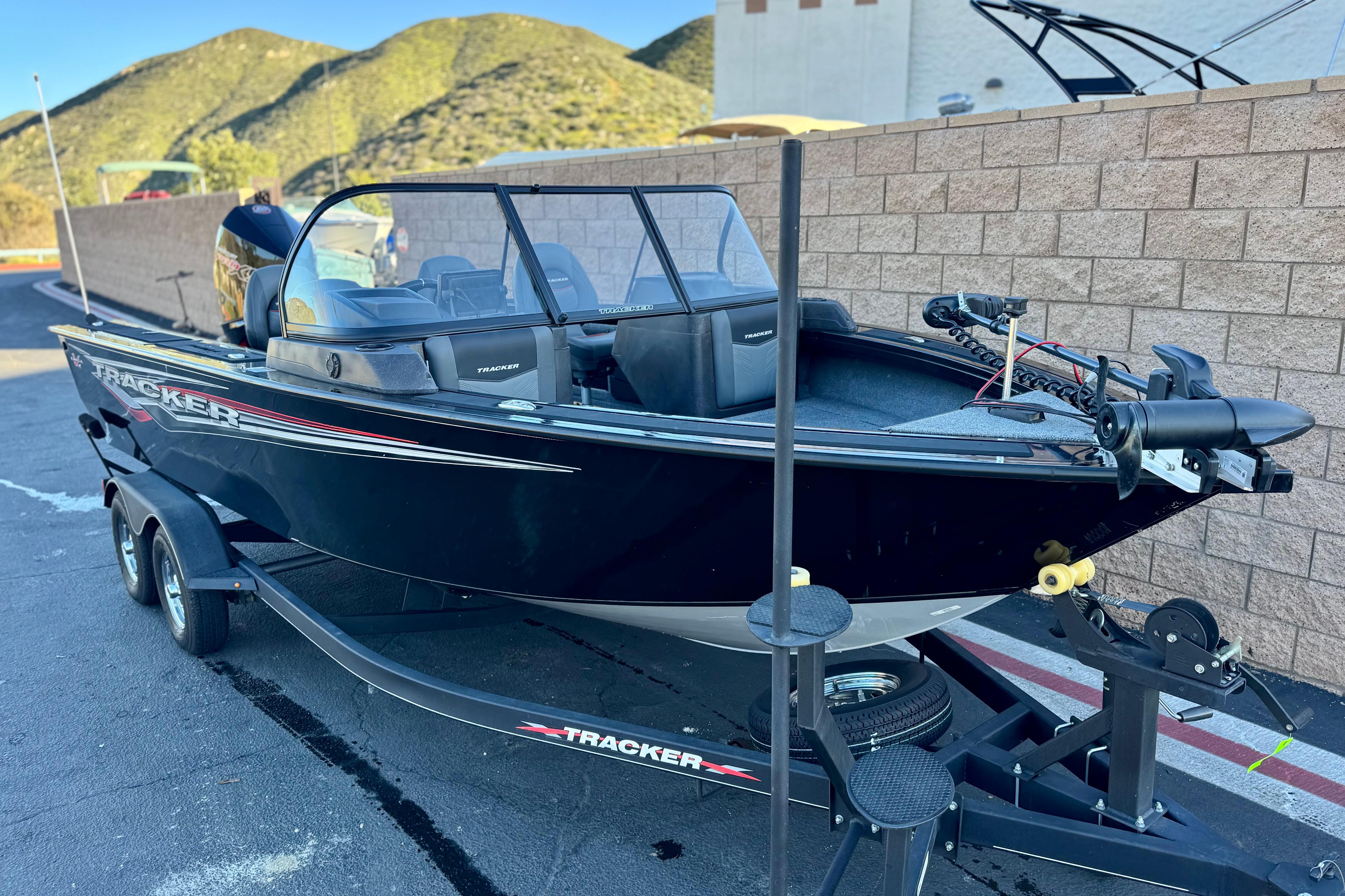 2023 Tracker Targa V-19 WT boat on trailer, parked outdoors with scenic mountain backdrop.