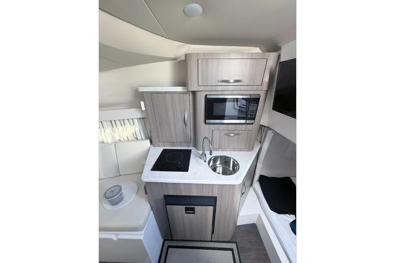 Yacht Photos Pics 2019 Regal 28 Express boat interior with kitchenette, featuring microwave, sink, and stove.