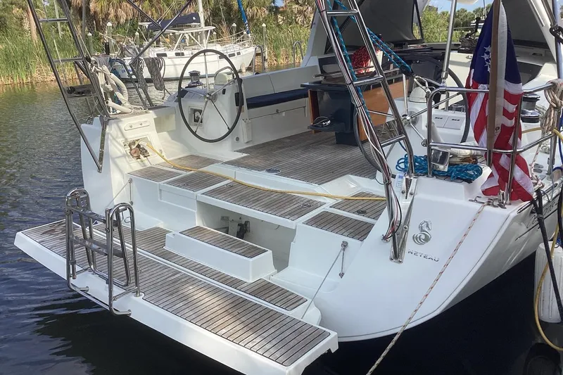At Last Yacht Photos Pics Beneteau Oceanis 45 sailboat, 2012 model, docked with American flag and wooden deck.