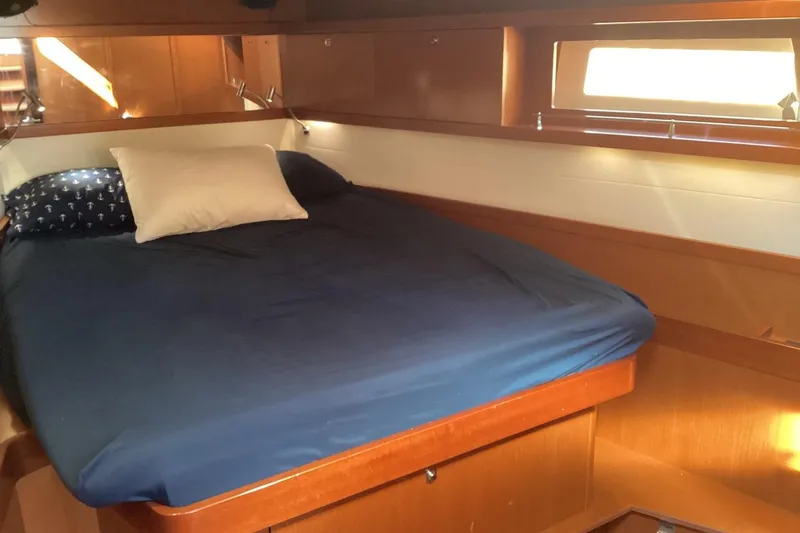 At Last Yacht Photos Pics Cozy cabin interior of 2012 Beneteau Oceanis 45 with blue bedding and wooden finish.