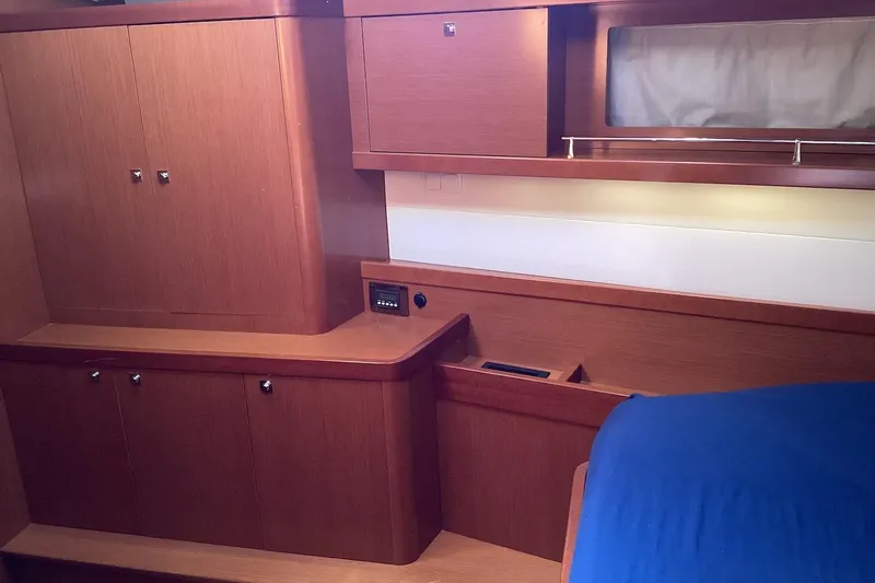 At Last Yacht Photos Pics Interior cabin of 2012 Beneteau Oceanis 45 yacht with wooden cabinetry and blue bedding.