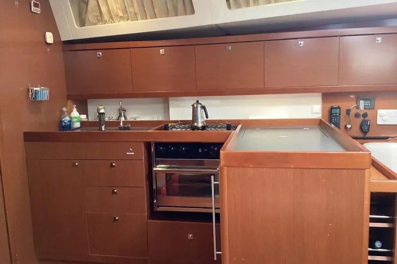 At Last Yacht Photos Pics Interior view of 2012 Beneteau Oceanis 45 yacht kitchen with wooden cabinetry and modern appliances.