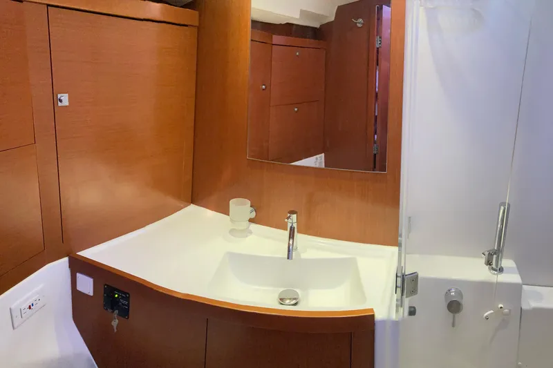 At Last Yacht Photos Pics Bathroom interior of 2012 Beneteau Oceanis 45 yacht with wooden cabinetry and modern sink.