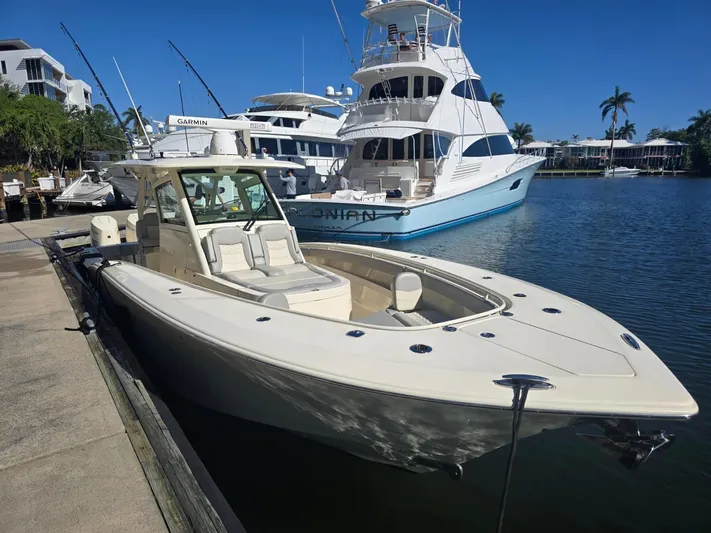  Yacht Photos Pics 2024 Scout 355 LXF boat docked in a marina, surrounded by other yachts.