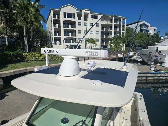  Yacht Photos Pics 2024 Scout 355 LXF boat docked, featuring Garmin xHD2 radar, with waterfront apartments in the background.