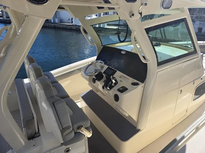  Yacht Photos Pics 2024 Scout 355 LXF boat interior with helm and seating, docked by the water.