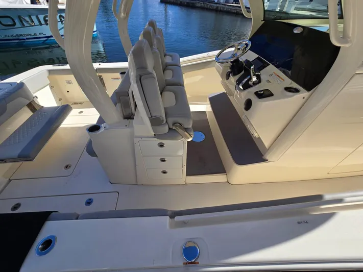  Yacht Photos Pics 2024 Scout 355 LXF boat interior with helm and seating, docked by the water.