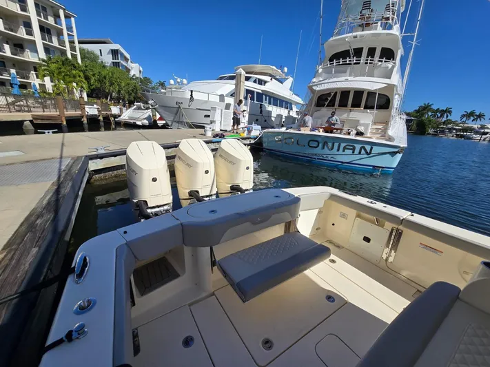  Yacht Photos Pics 2024 Scout 355 LXF boat docked with triple outboard engines, marina view.
