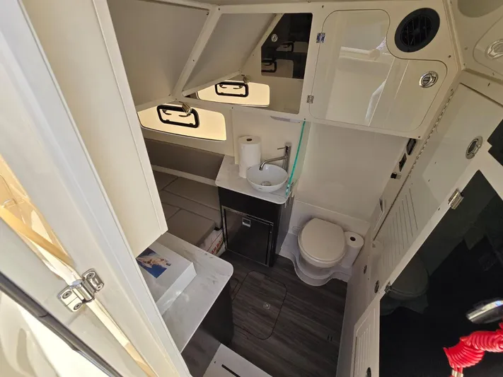  Yacht Photos Pics 2024 Scout 355 LXF boat bathroom with sink, toilet, and storage cabinets.