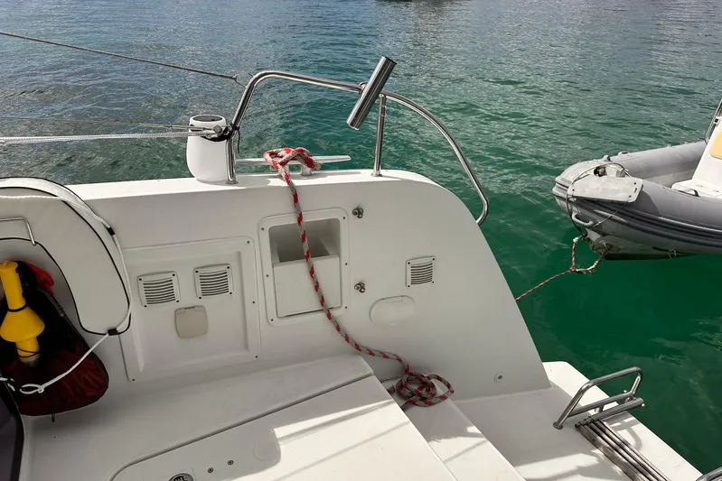  Yacht Photos Pics Stern view of 2016 Lagoon 42 catamaran with dinghy attached, on calm water.