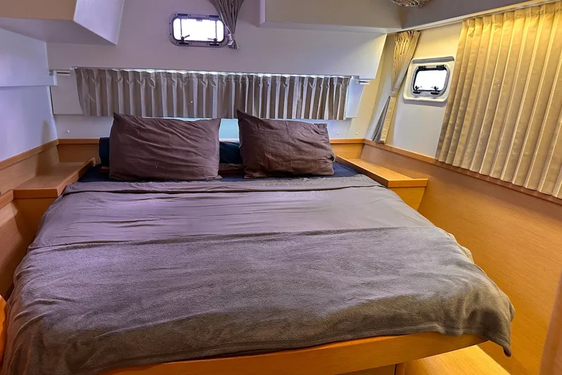  Yacht Photos Pics Cozy bedroom interior of 2016 Lagoon 42 catamaran with wooden accents and soft lighting.