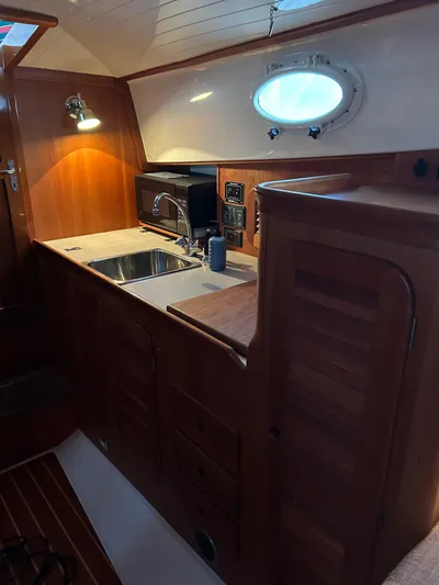  Yacht Photos Pics 2001 Hinckley Classic 36 Picnic Boat interior with wooden cabinetry and compact kitchen area.