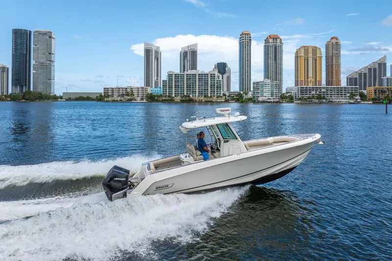 My Sherry III Yacht Photos Pics 2018 Boston Whaler 280 Outrage cruising on water with city skyline backdrop.