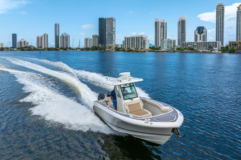 My Sherry III Yacht Photos Pics 2018 Boston Whaler 280 Outrage cruising on water with city skyline backdrop.