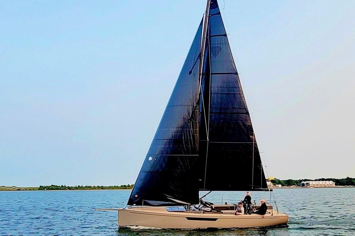 Saffier 33 Life 2022 sailboat with black sails on calm water.