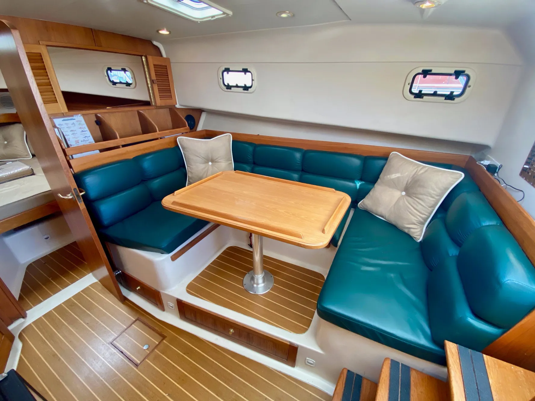 Interior of a 2000 Mainship Pilot 34 yacht with wood flooring and green upholstery.